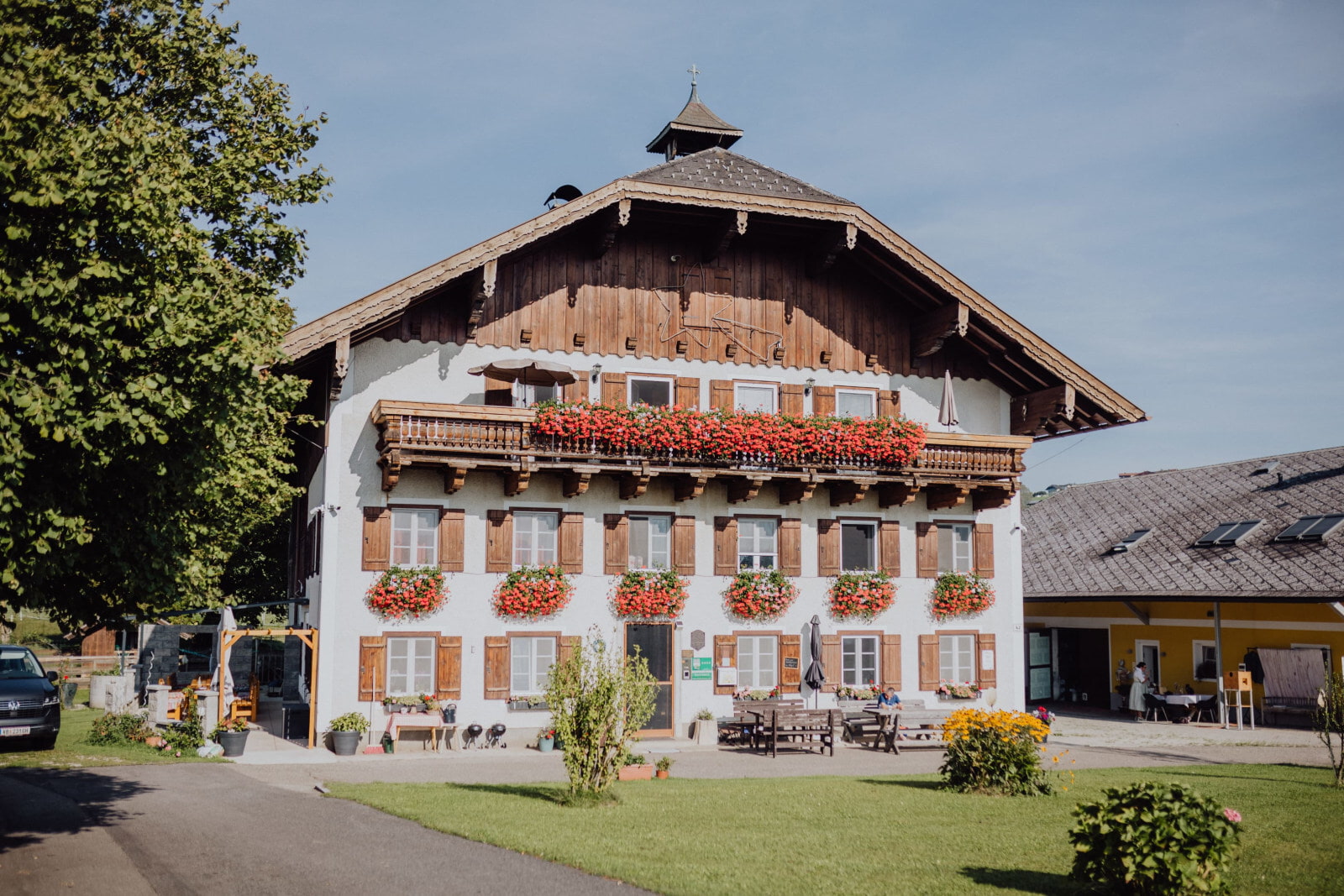 Ferienhof Hinterstrasser Traditionelles Alpen-Chalet mit Holzbalkon, Blumenkästen und Außentischen vor dem Eingang.
